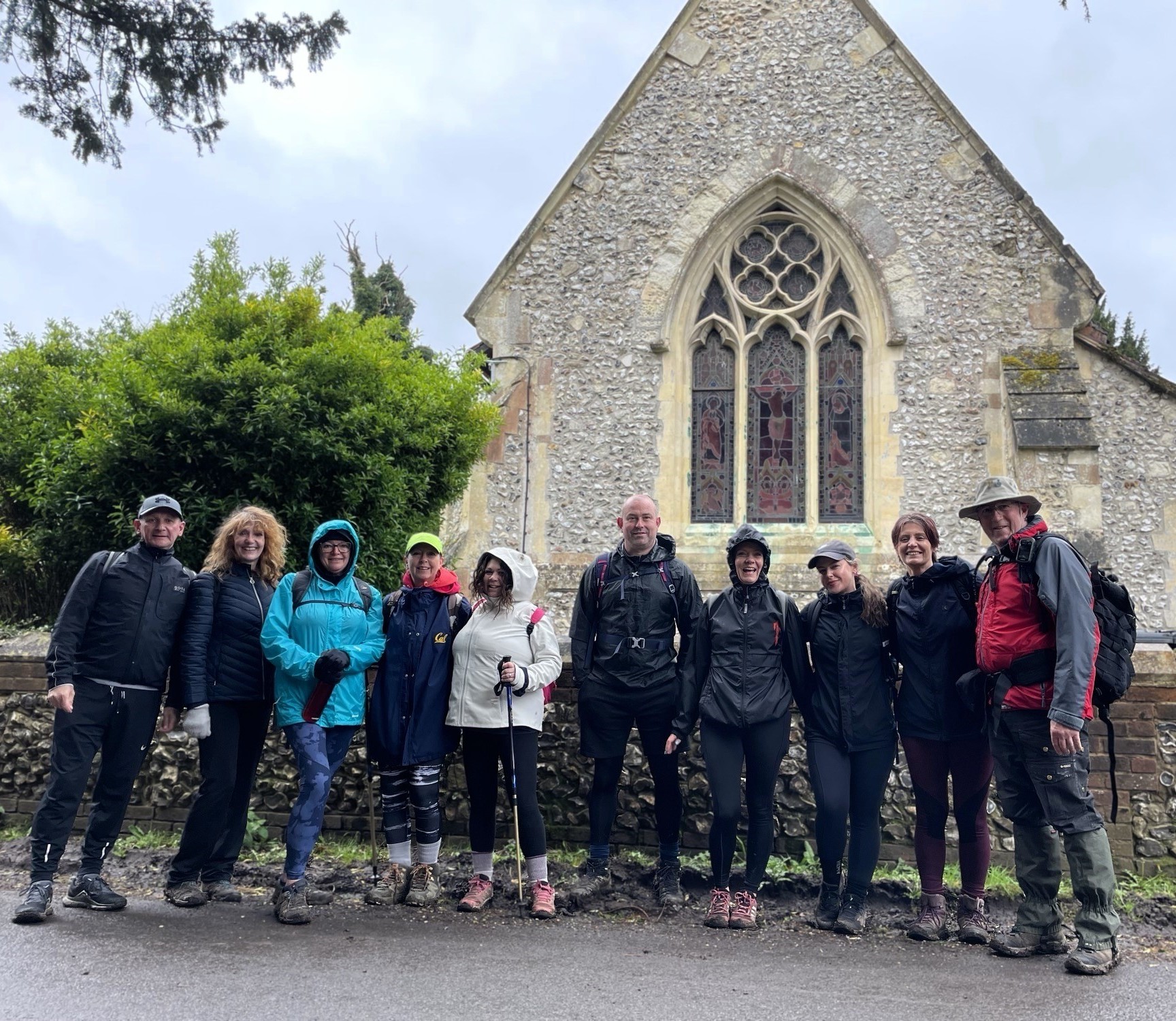 Group of hikers posing outside a historic stone church, ready for Jacqui's 78-mile challenge.